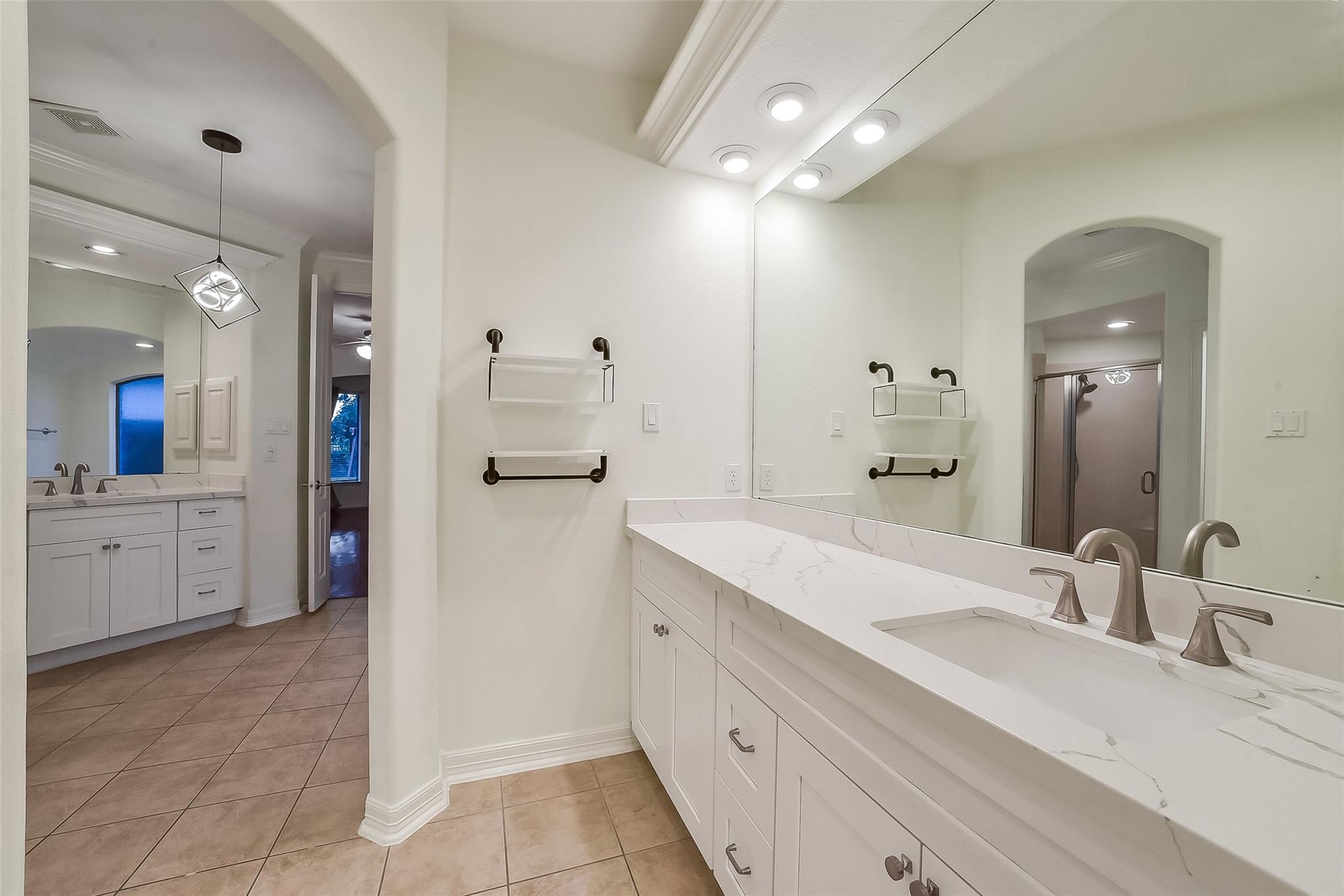 Bathroom with a long double-sink vanity, marble-look countertop, and glass-enclosed shower.