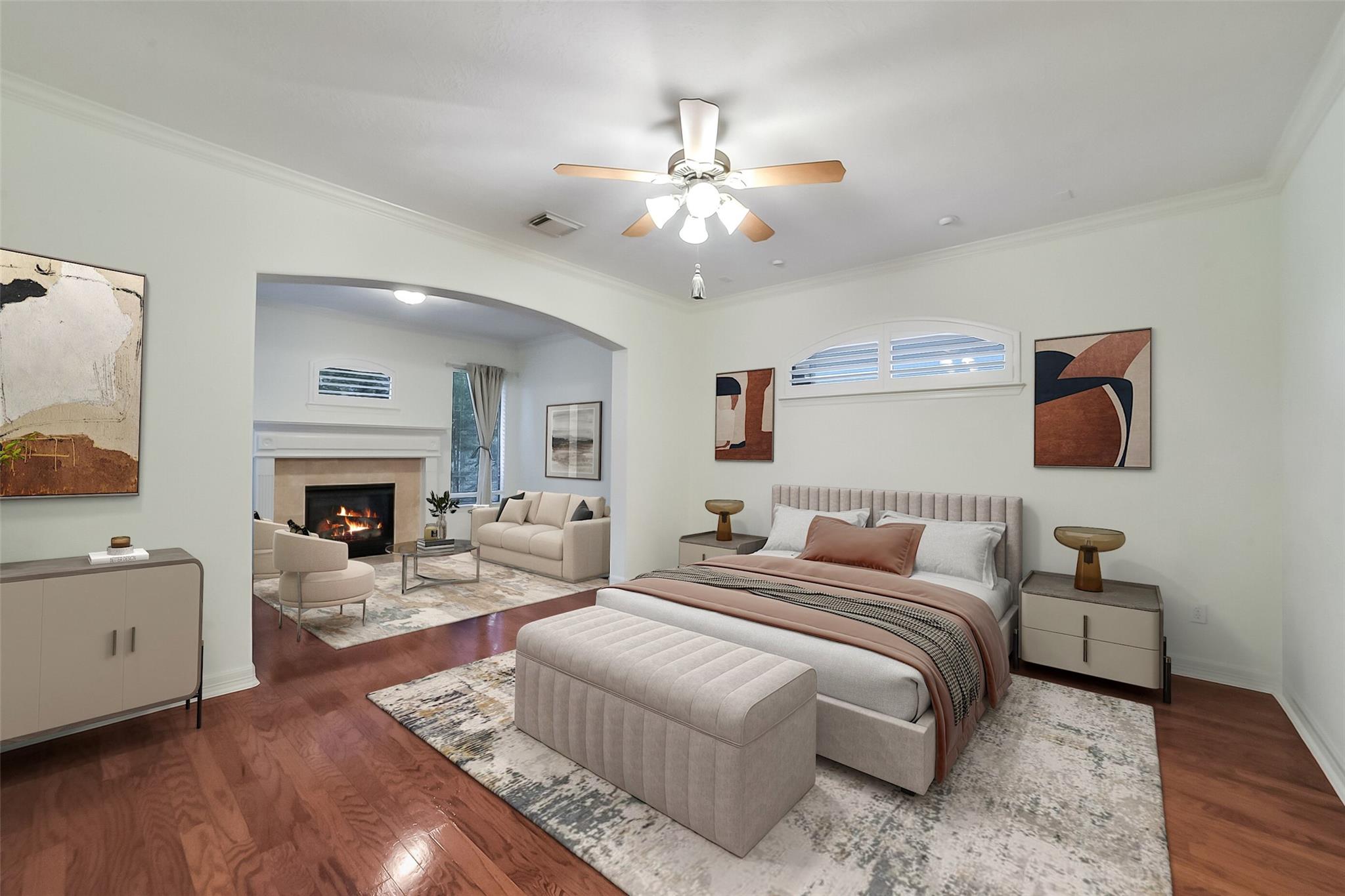 Furnished bedroom with an upholstered bed and an adjoining sitting area with a lit fireplace.