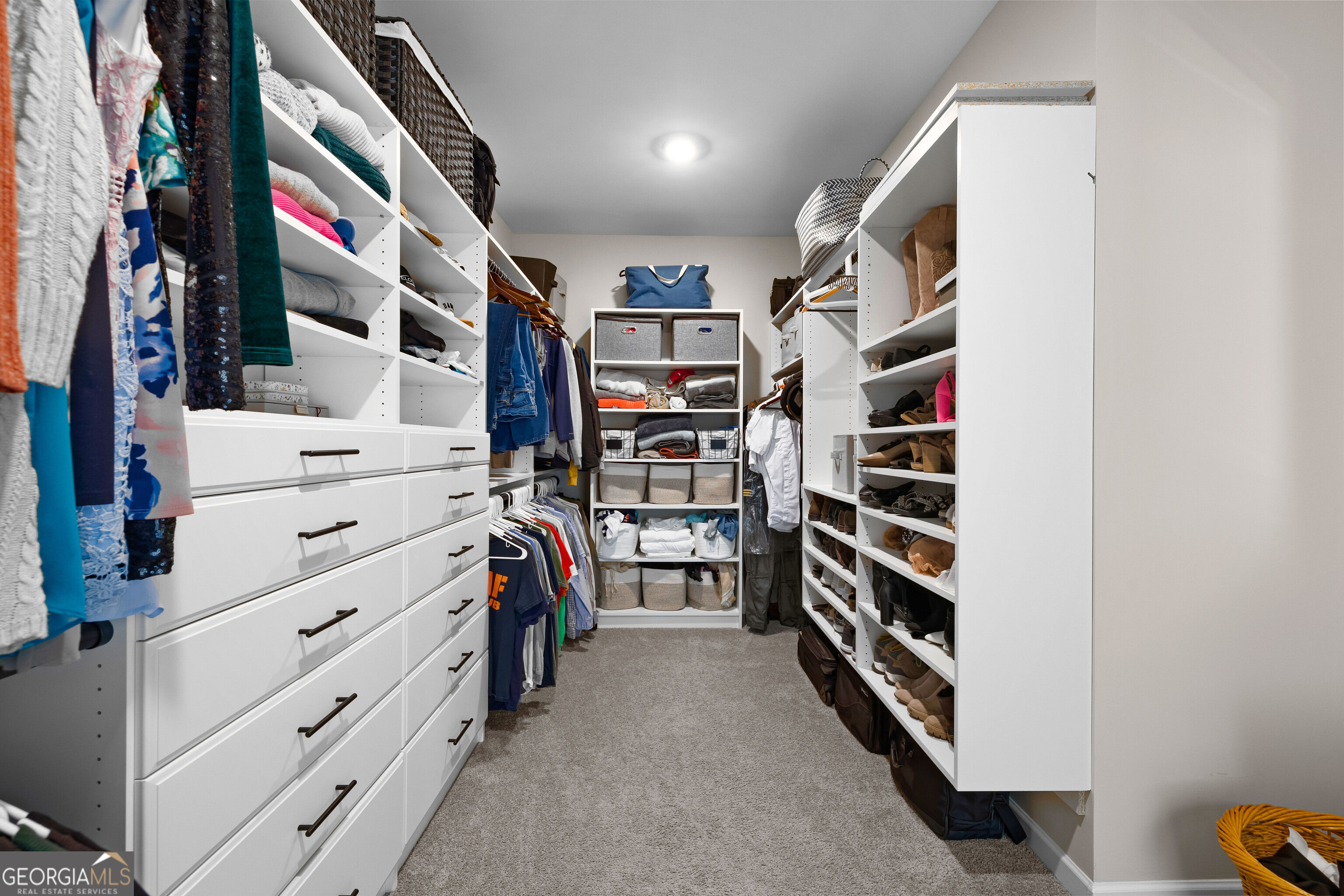 Walk-in closet with built-in drawers, clothing racks, and extensive shoe shelving.