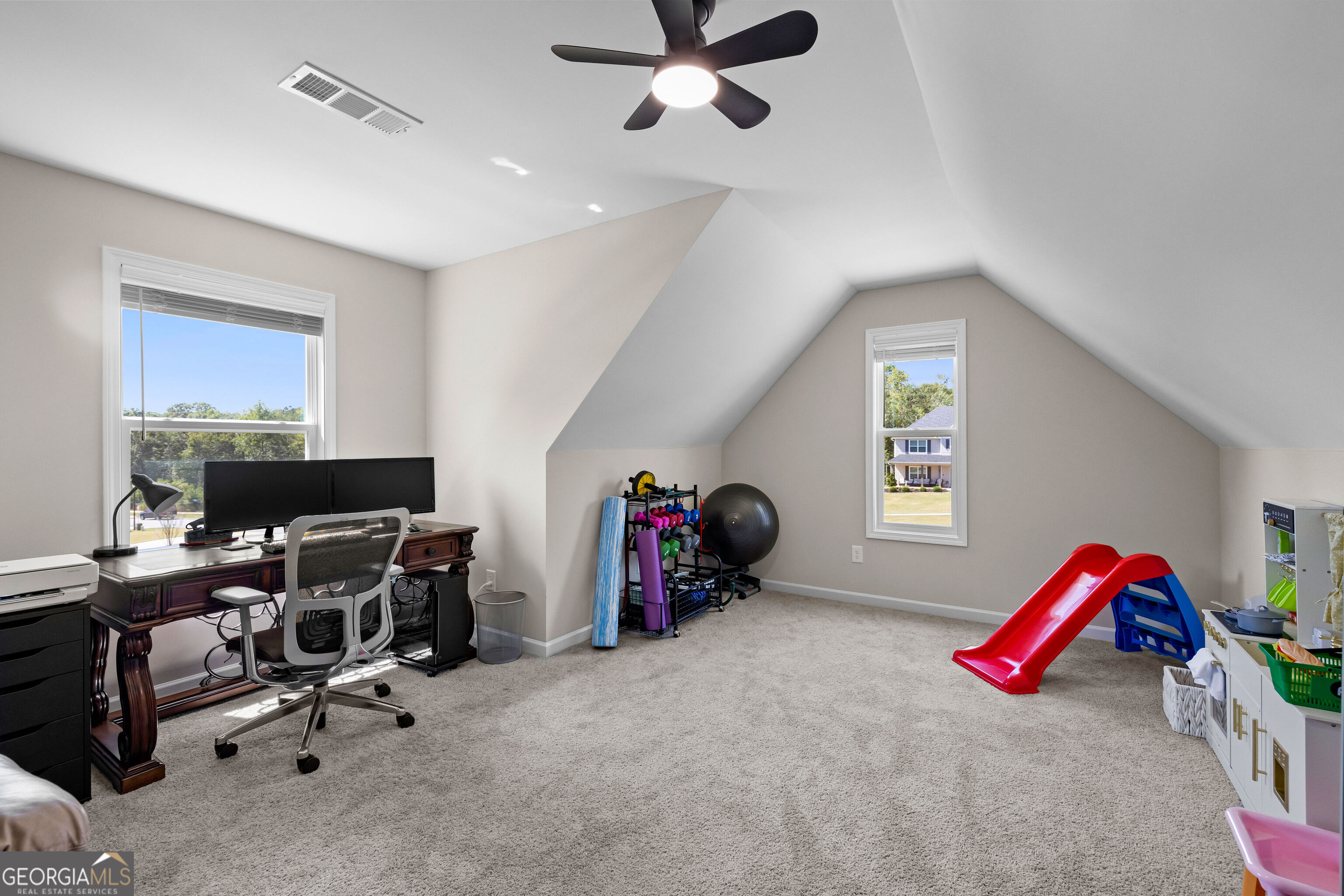 Upstairs bonus room with a desk, exercise equipment, and a red child’s slide.