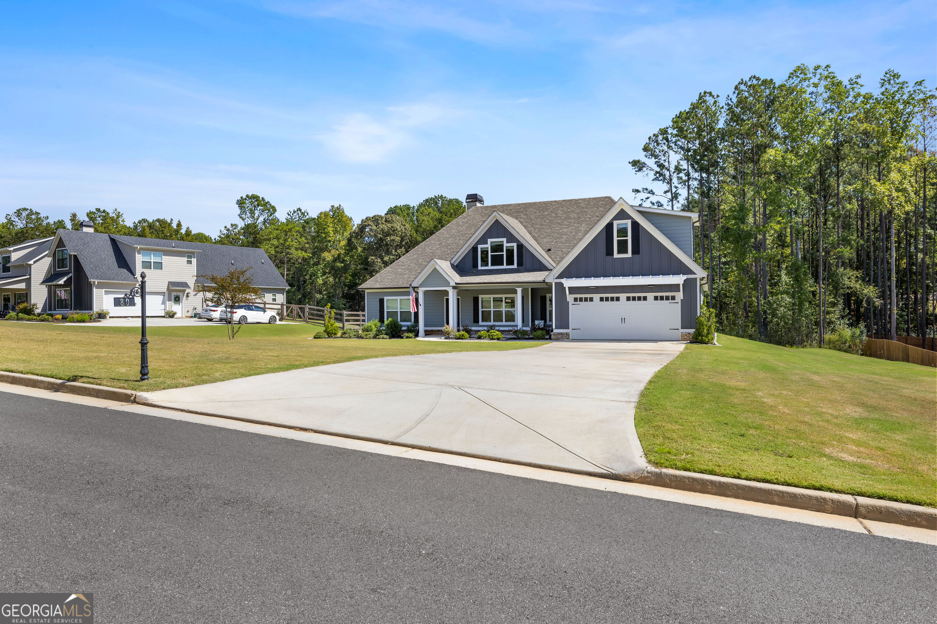 Gray two-story house with white trim, front porch, and a broad curved driveway.