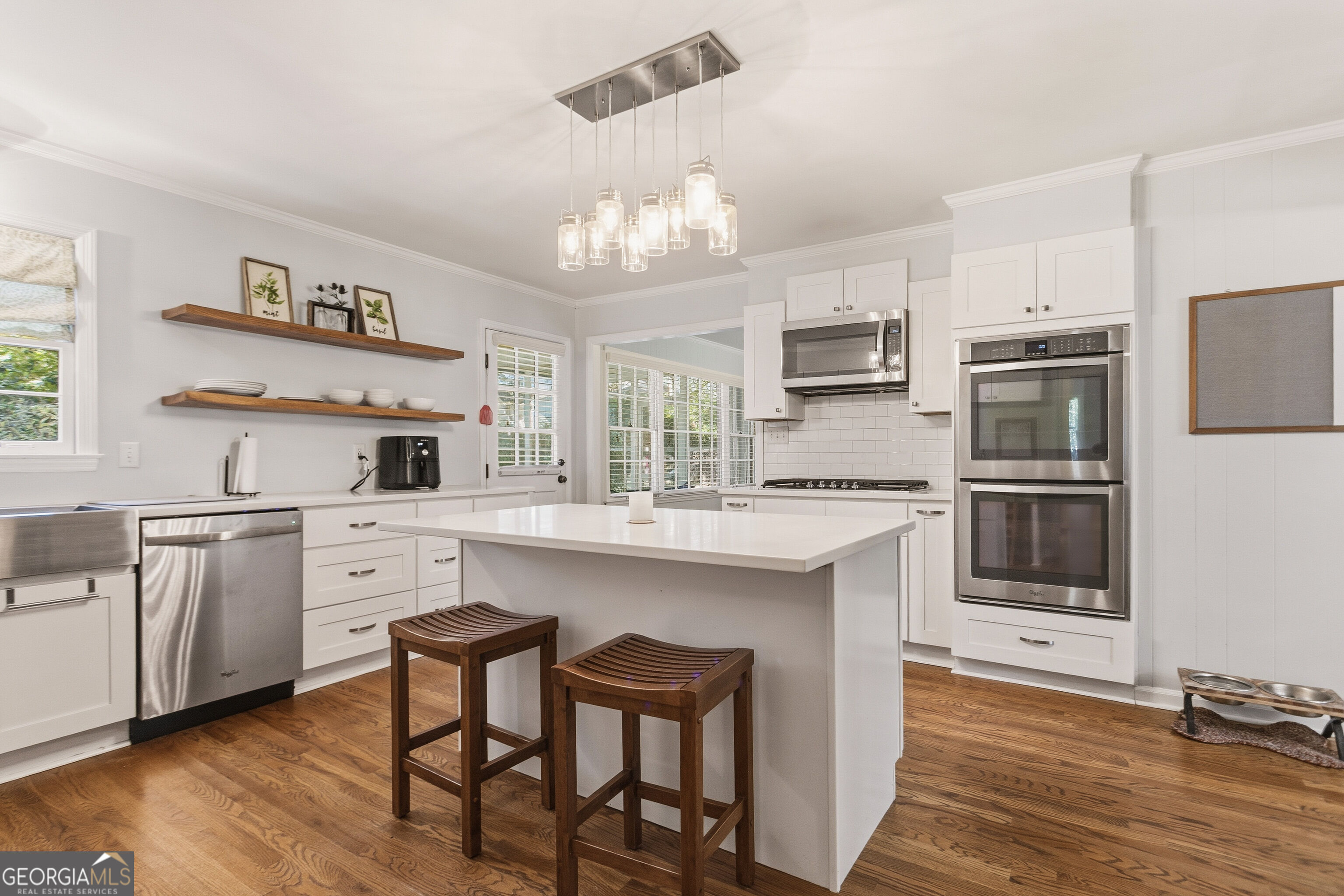 Kitchen with a large white island, stainless steel appliances, and hardwood floors.
