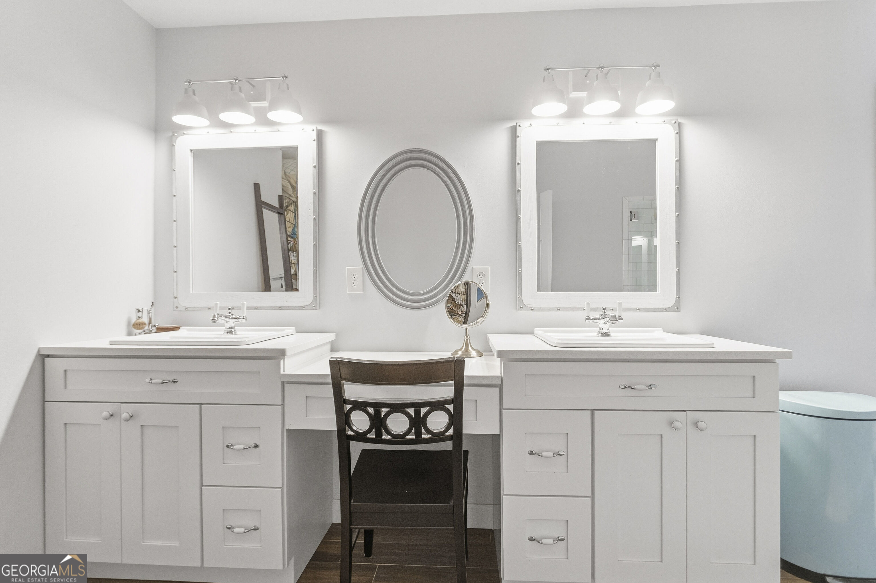 Bathroom with a white double vanity, framed mirrors, and a central dressing area.