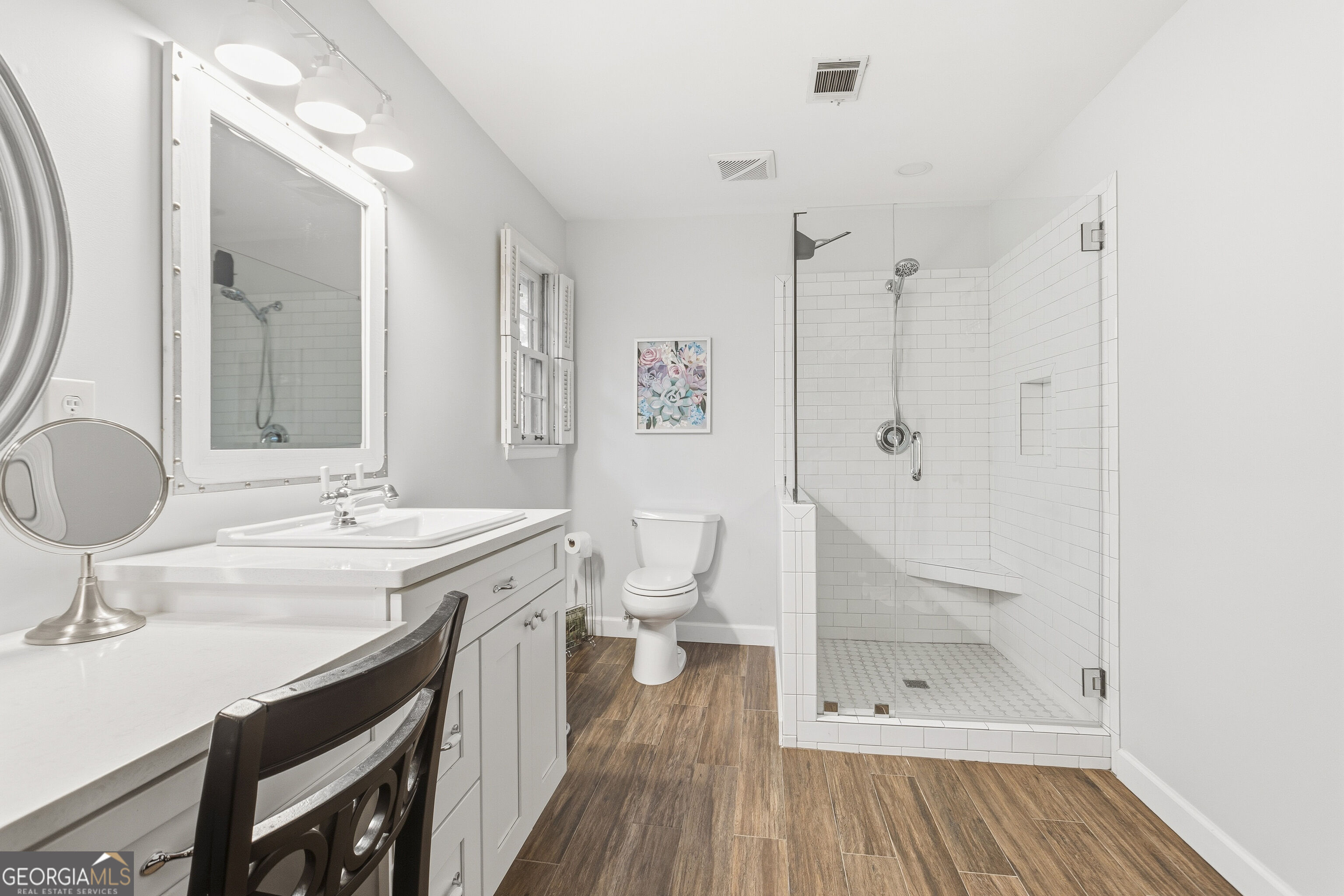 Bright bathroom with a white vanity and a spacious subway-tile walk-in shower with a built-in bench.