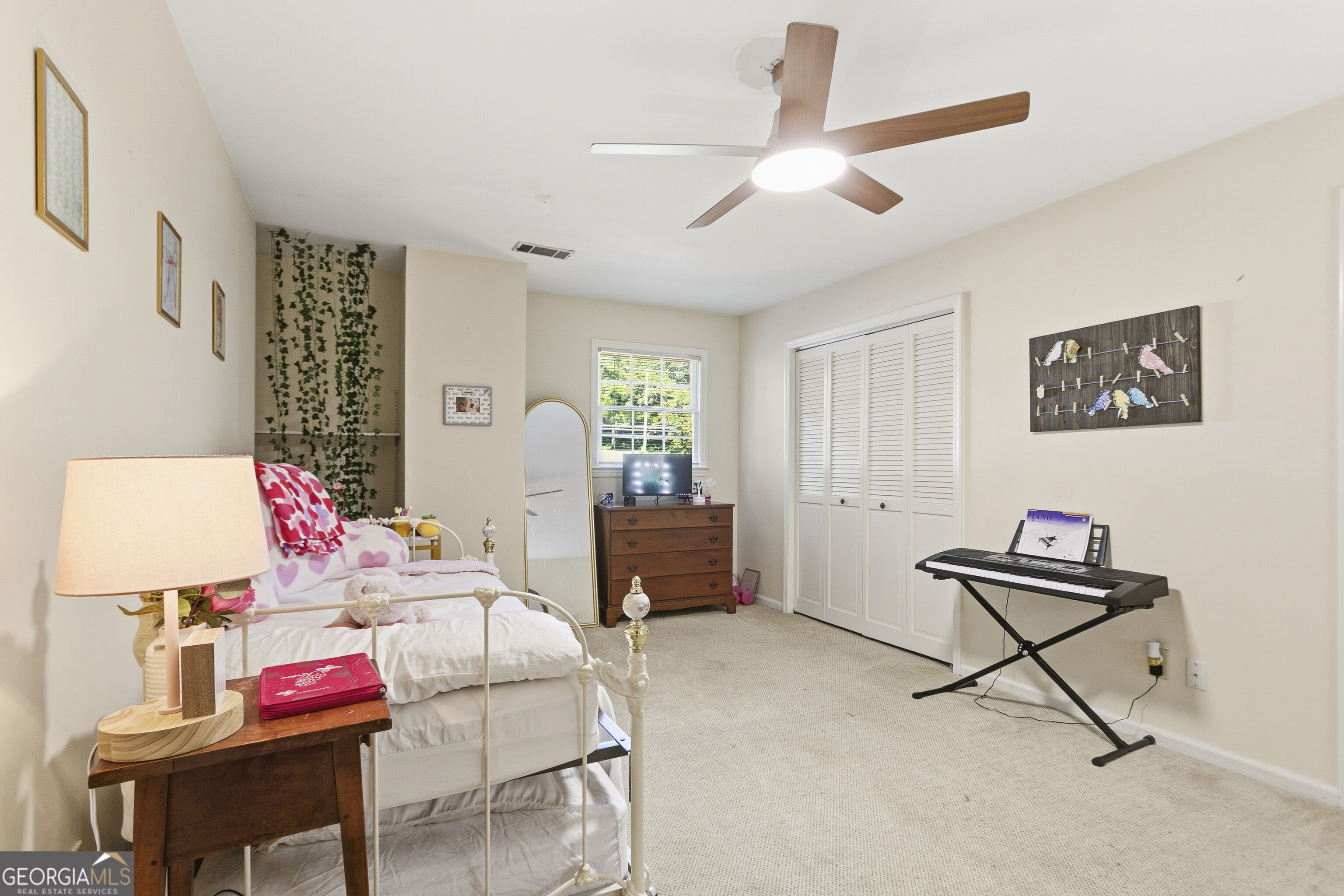 Furnished bedroom with pink heart-patterned bedding, a white metal bed, and an electronic keyboard.