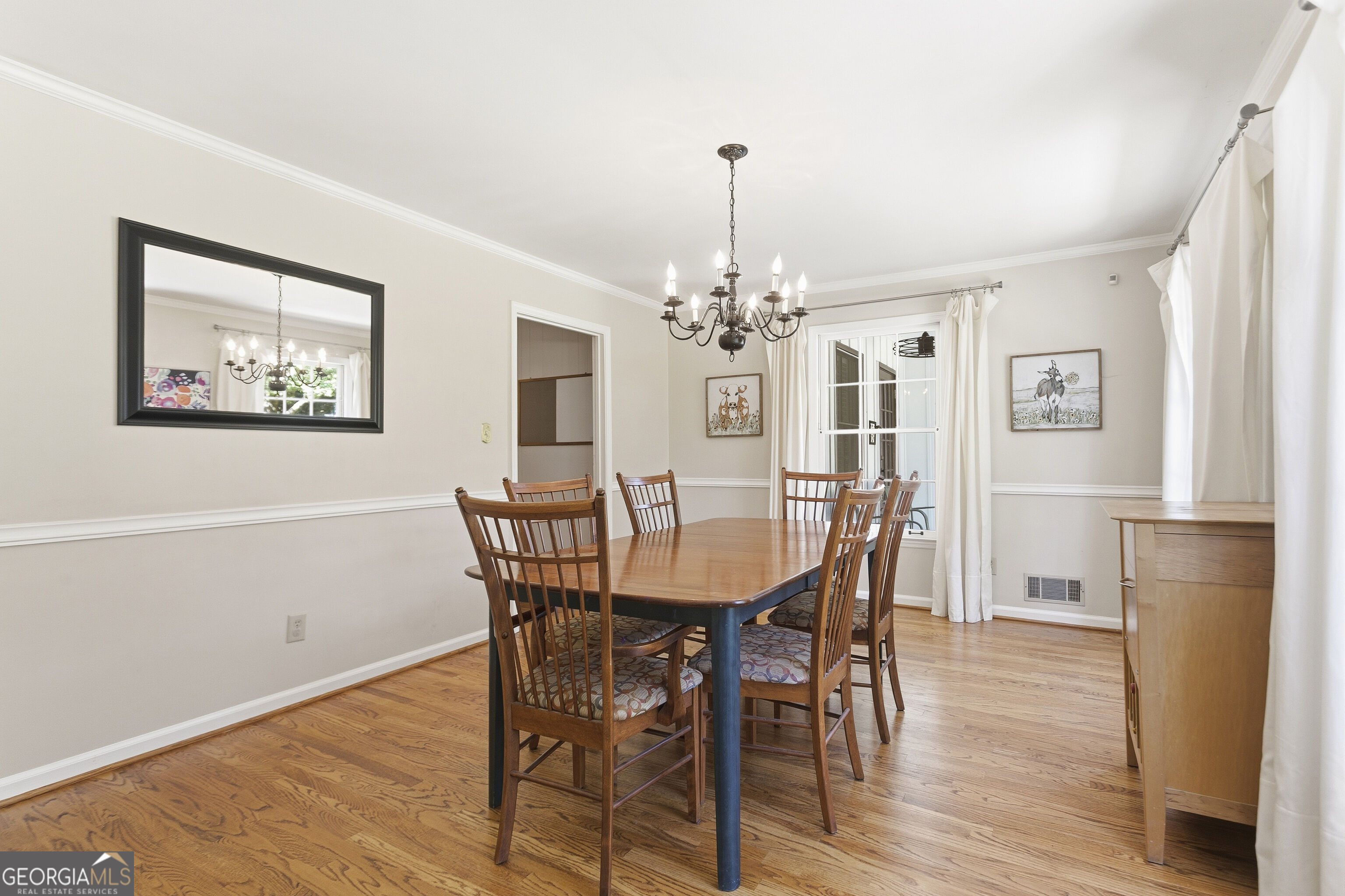 Dining room with a wooden table and chairs, hardwood floors, and a dark chandelier.