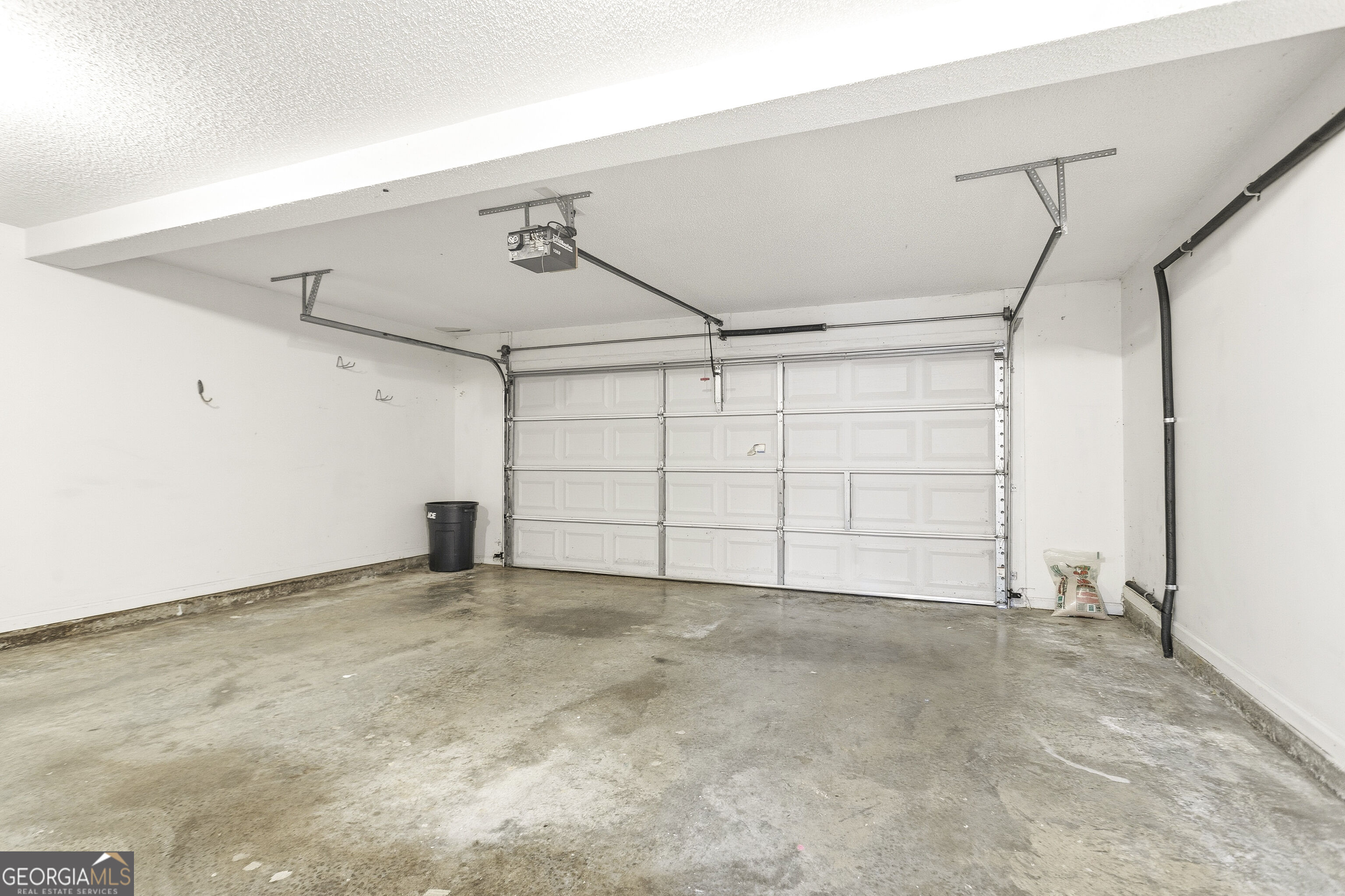 Empty garage with a wide white sectional door and bare concrete floor.