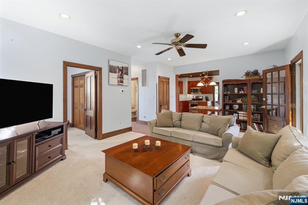 Living room with beige sofas, wooden coffee table, built-in bookcases, and an open view into the kitchen.