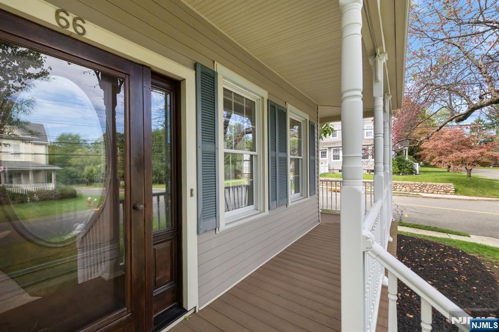 Front porch with a dark wood entry door, blue shutters, white columns, and a covered deck.
