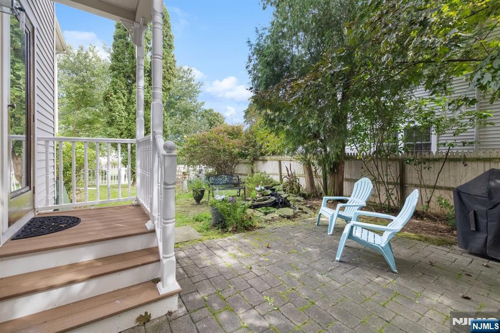 Backyard patio with blue Adirondack chairs, garden beds, and a white-railed porch.