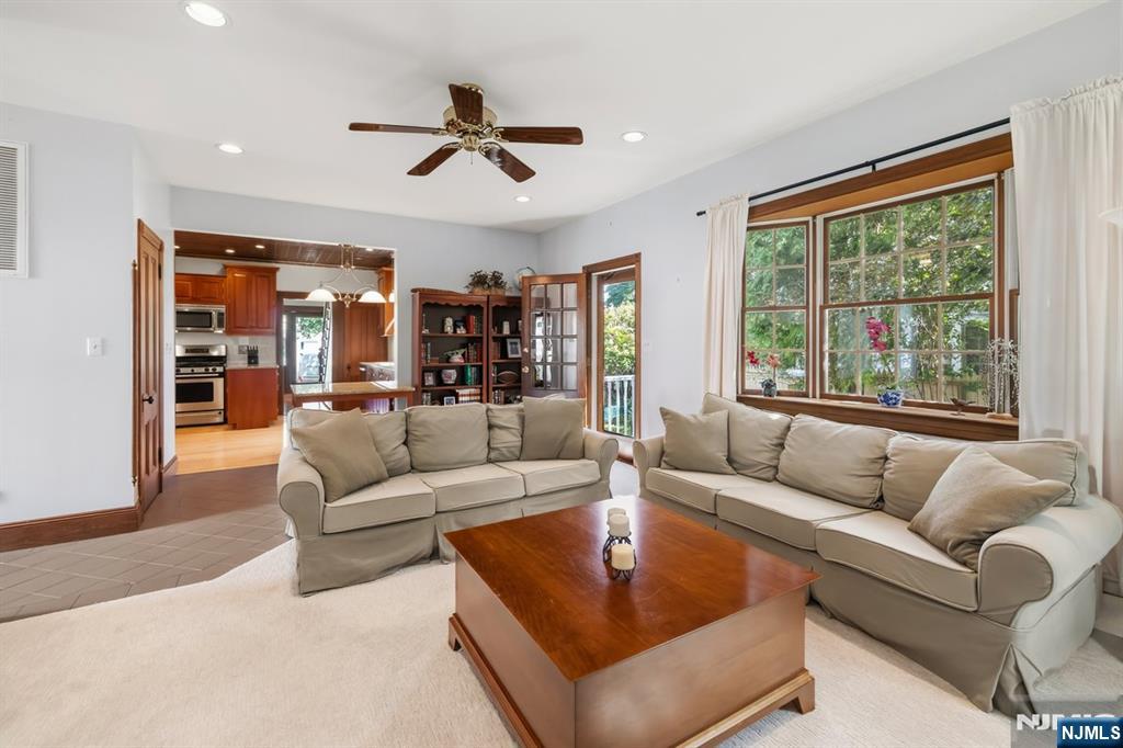 Living room with beige sofas, a wooden coffee table, and large windows overlooking greenery.