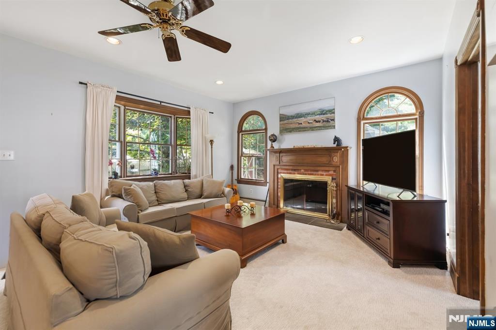 Living room with a wood-trimmed fireplace, arched windows, and beige sofas.