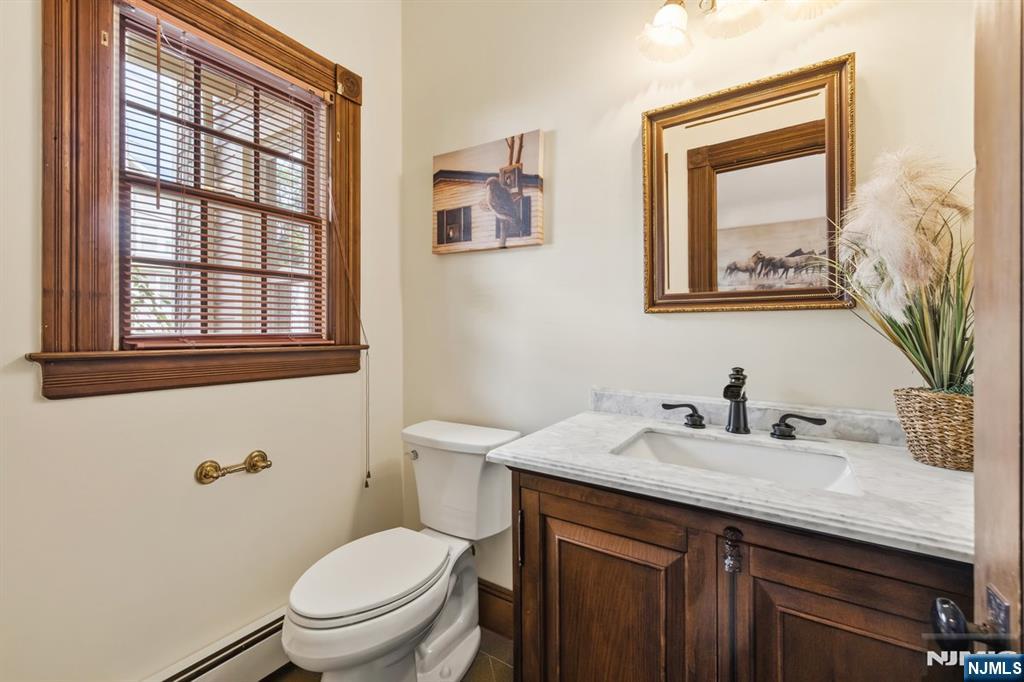 Bathroom with a dark wood vanity, marble countertop, and wood-trimmed window.
