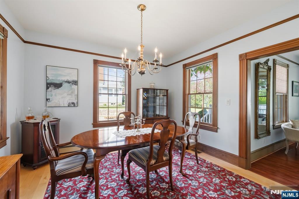 Dining room with a polished oval table, chandelier, and red patterned rug.