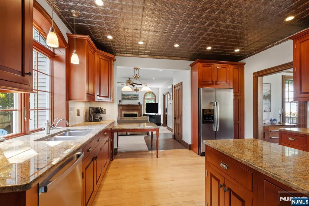 Kitchen with cherry cabinets, granite countertops, stainless-steel refrigerator, and a decorative tin ceiling.