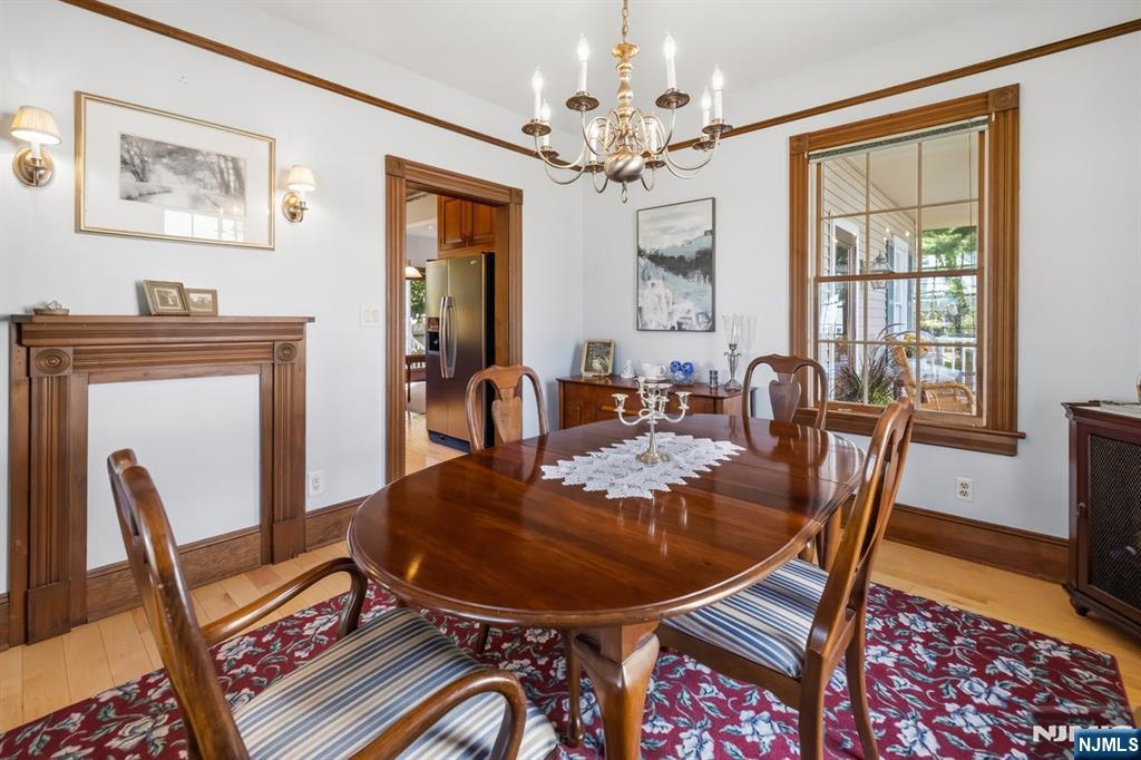 Dining room with a polished oval table, chandelier, and wood-trimmed windows.