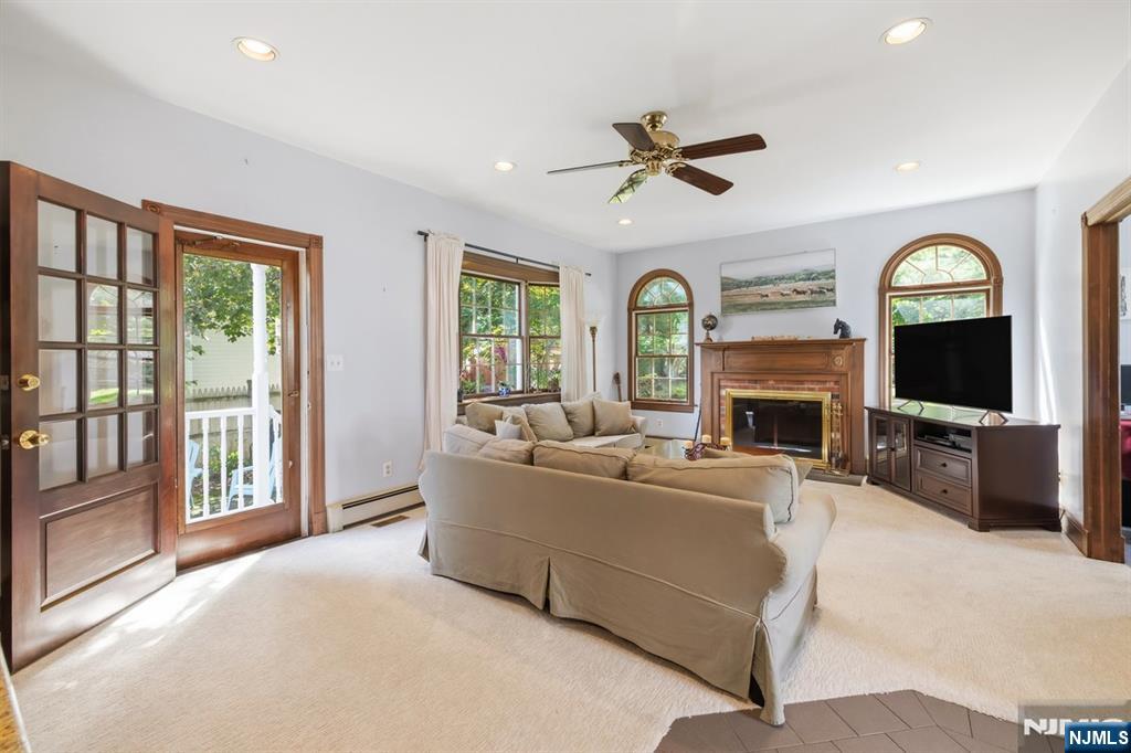 Living room with a beige sectional, wood-trimmed fireplace, arched windows, and French doors to a porch.