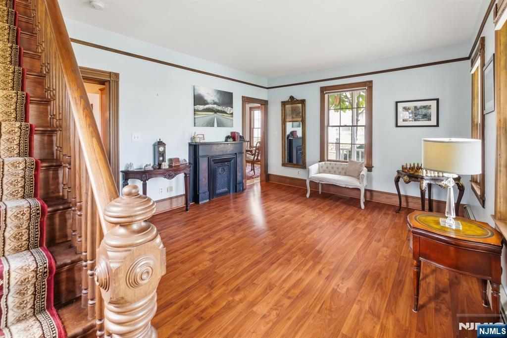 Entry hall with a carved wooden staircase, hardwood floors, and a fireplace.