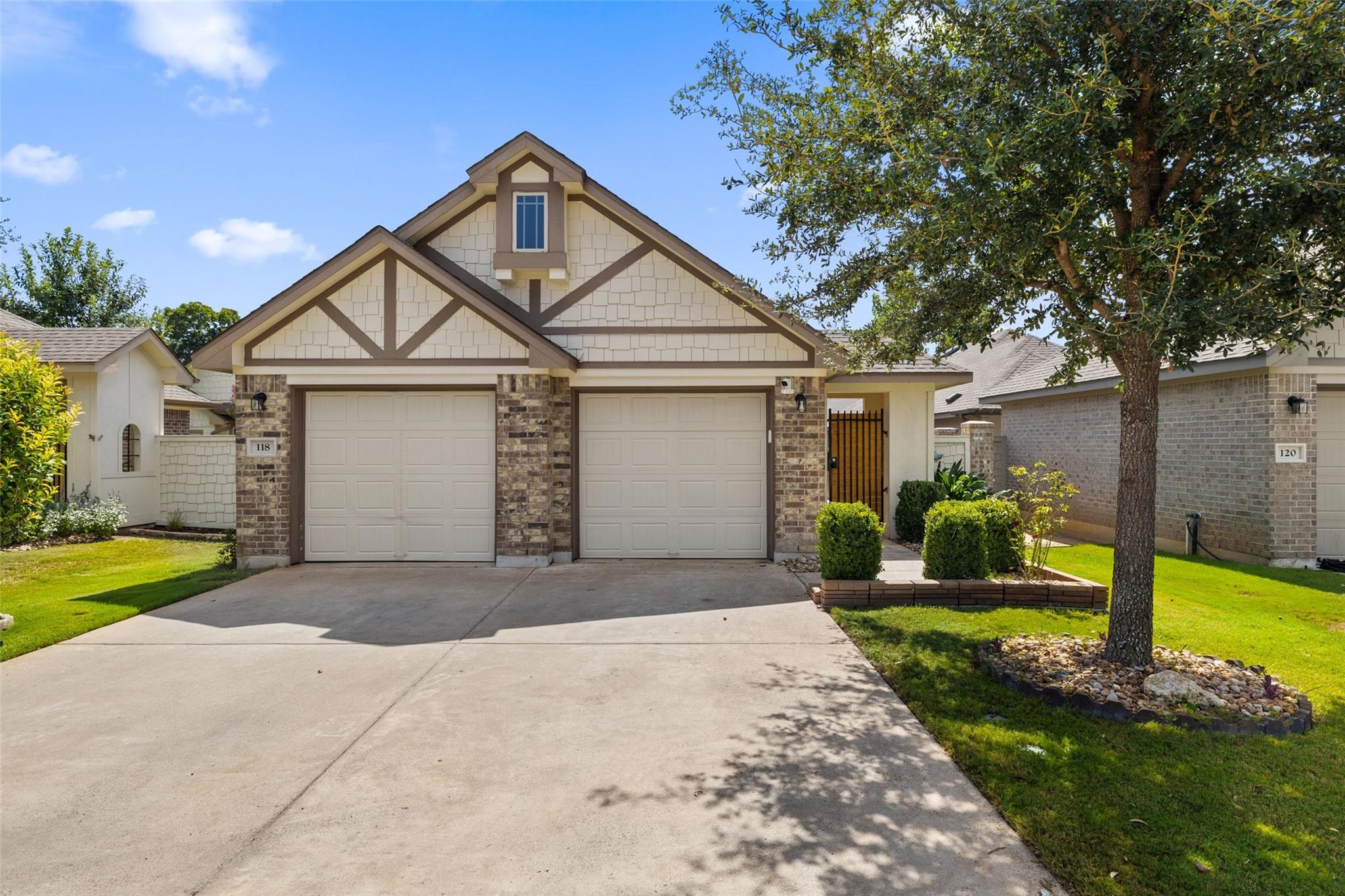 Detached home with two garage doors, stone accents, and a landscaped front yard.