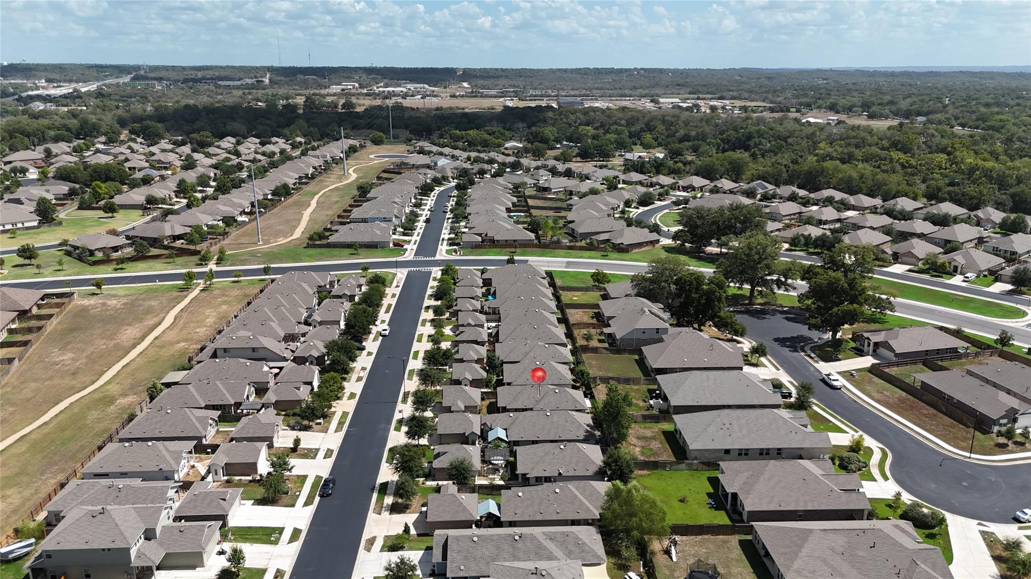 Aerial view of a subdivision with a red pin marking a home among rows of houses.