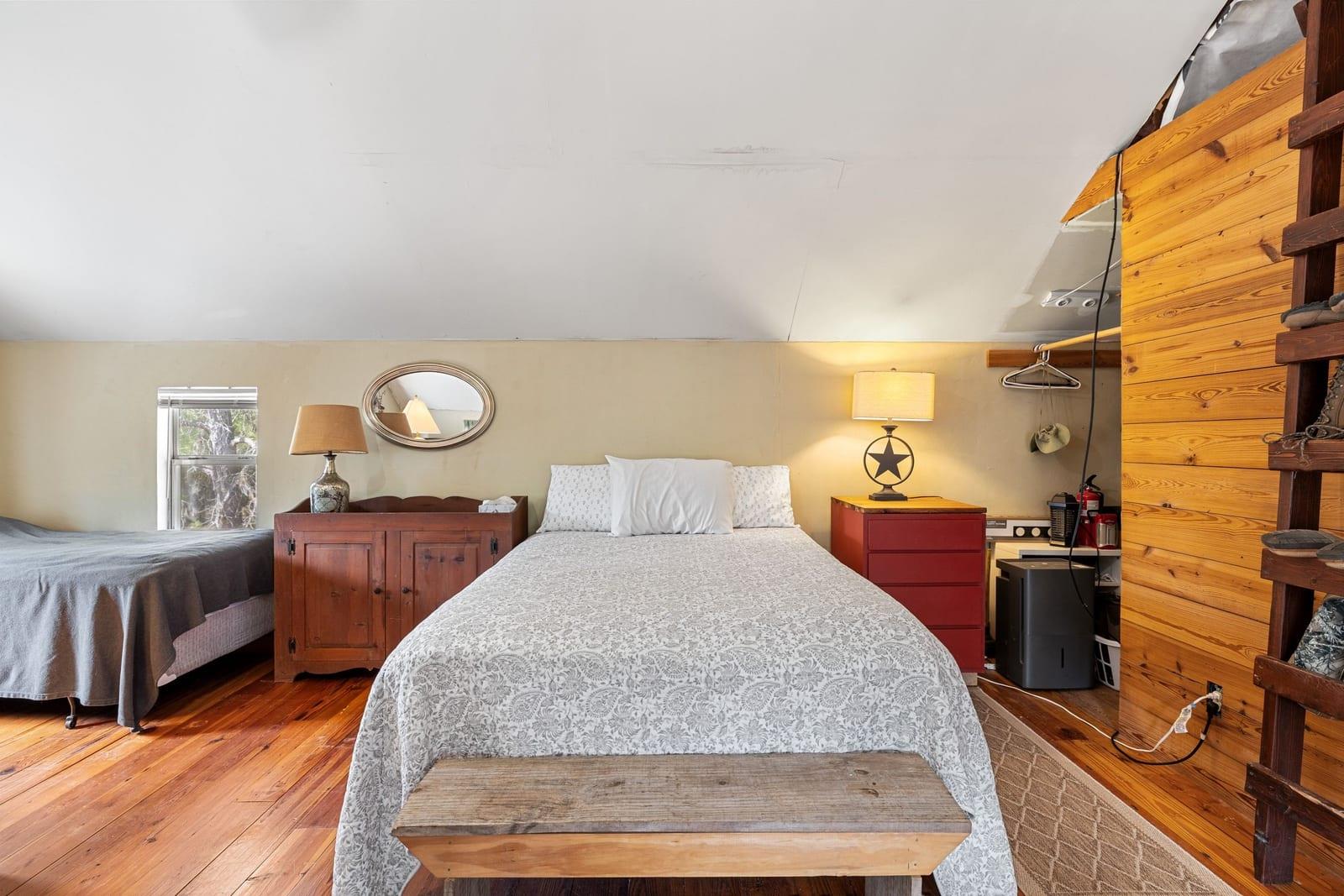 Bedroom with two beds, warm wood floors, and a wooden partition.