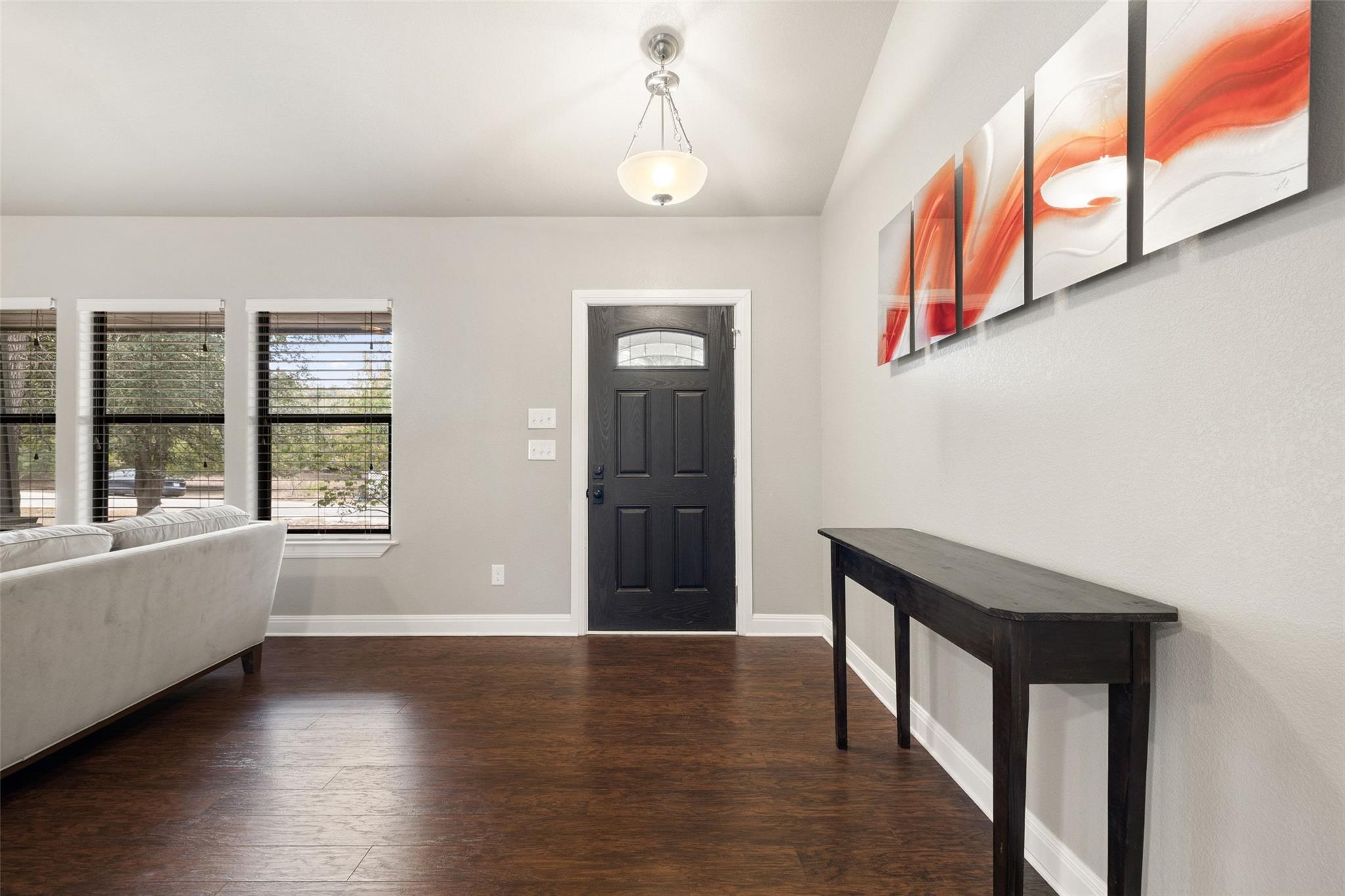 Entryway with a black front door, dark wood floors, and orange abstract wall art.