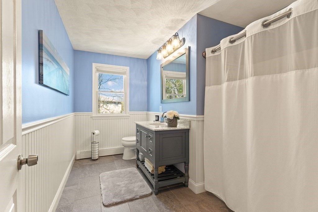 Bathroom with a gray vanity, blue walls, white beadboard, and a shower curtain.