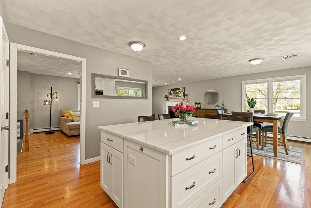 Bright kitchen with a large white island opening to a dining area and living room.
