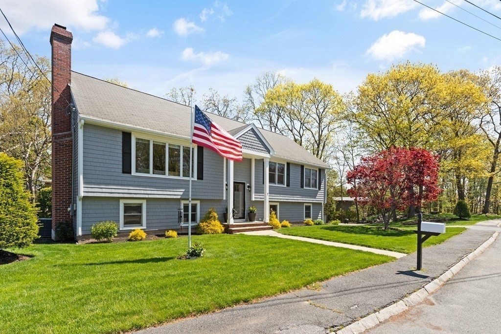 Gray split-level home with a brick chimney and American flag beside the front entrance.