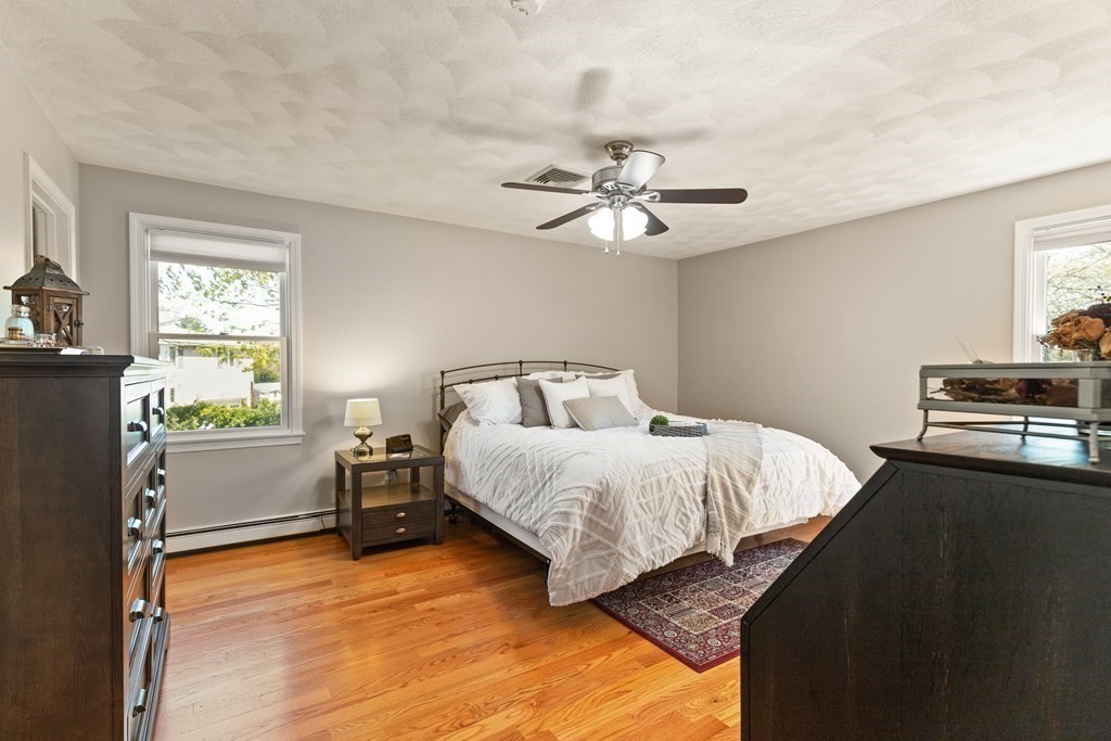 Bedroom with a white bed, dark wood furniture, hardwood floors, and a patterned rug.