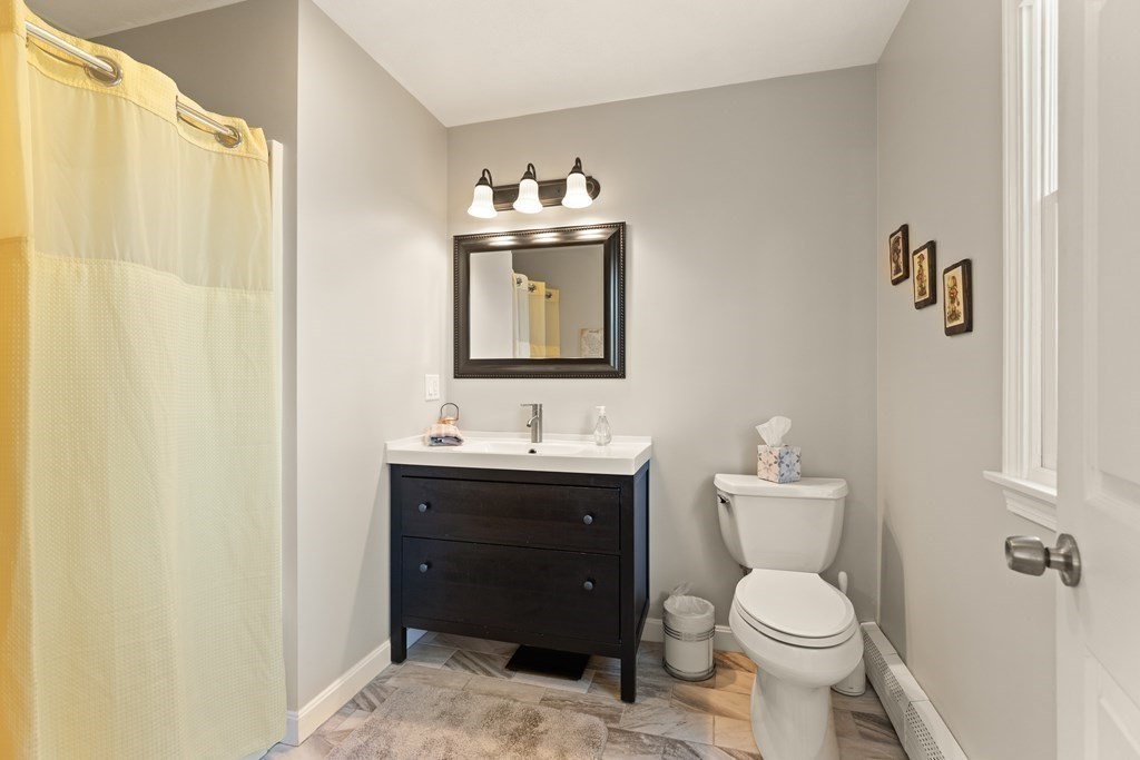 Bathroom with a dark wood vanity, yellow shower curtain, and tiled floor.