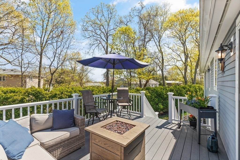 Furnished backyard deck with sectional seating, a square fire table, and a large umbrella.