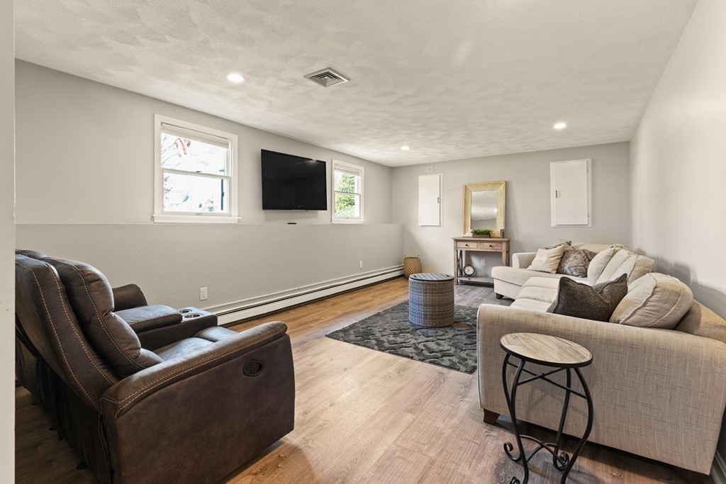 Living room with a beige sectional, leather recliners, patterned rug, and wall-mounted television.