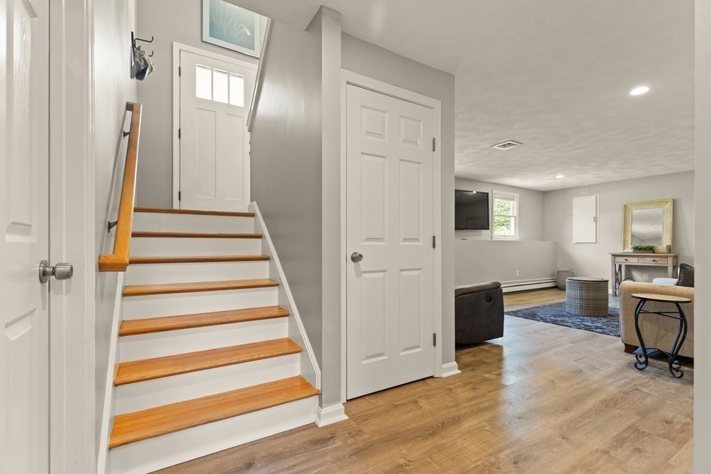 Entryway staircase with wooden treads beside an open living area.