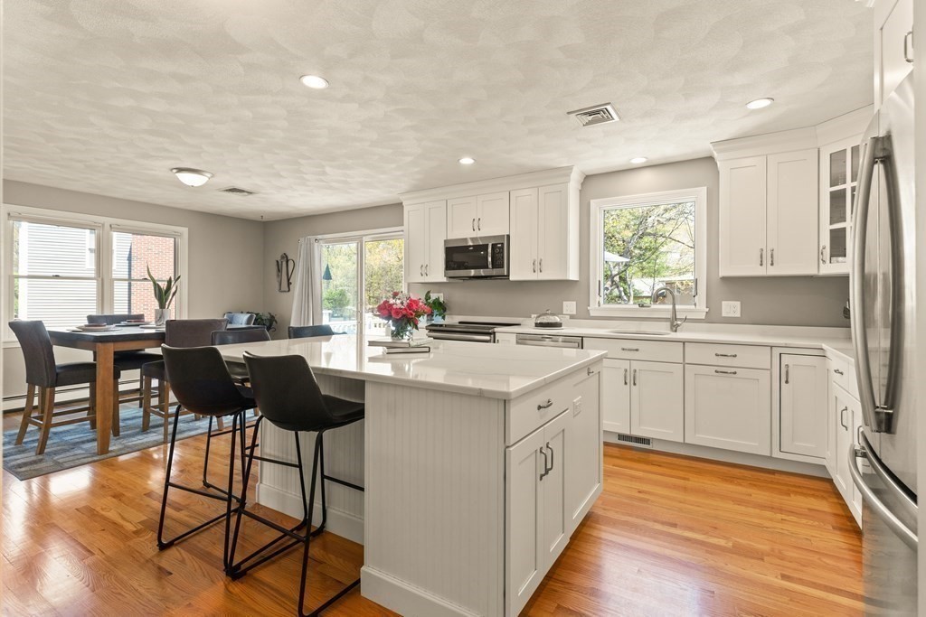 Kitchen with a large white island, stainless steel appliances, and an adjoining dining area.