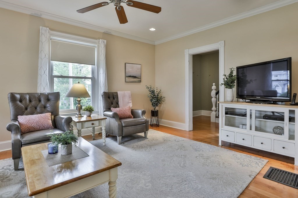 Living room with two leather armchairs, a large rug, and a TV on a white console.