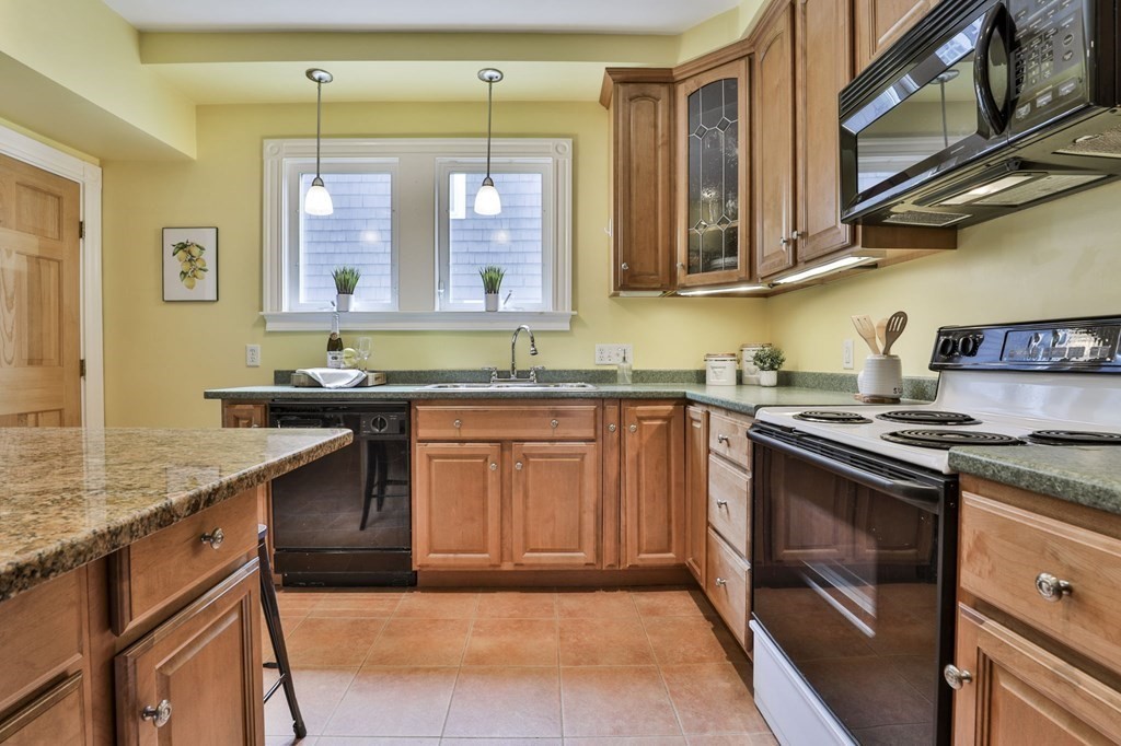 Kitchen with warm wood cabinets, green stone countertops, and stainless steel appliances.