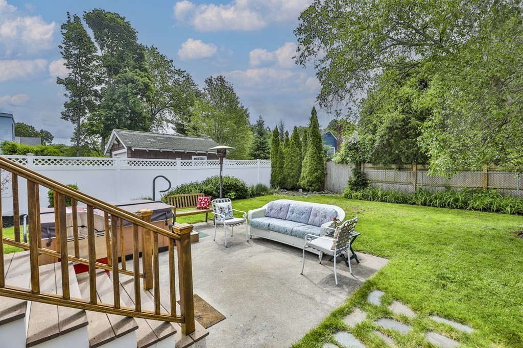 Backyard patio with a hot tub, outdoor seating, and fenced lawn.
