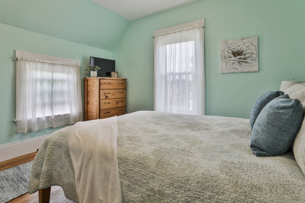Bedroom with a large gray-quilted bed, teal walls, and a wooden dresser.