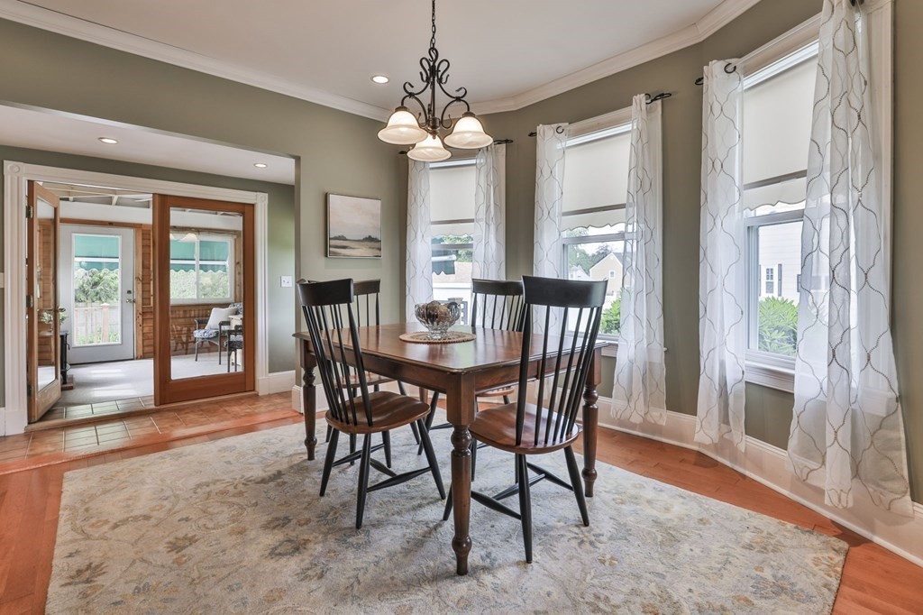 Dining room with a dark wood table, patterned rug, and glass doors to a sunroom.