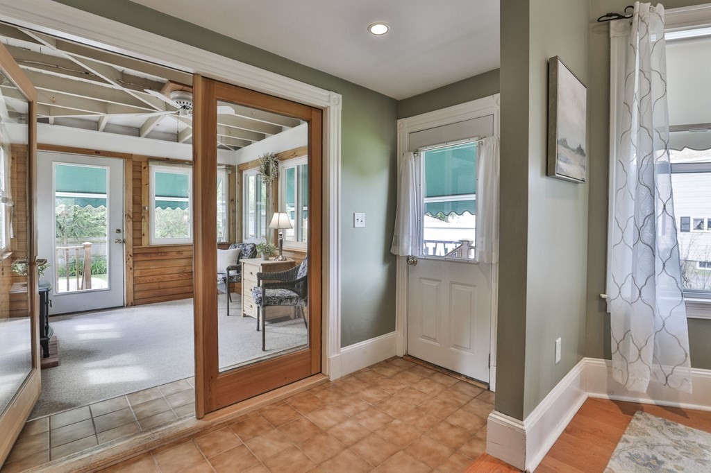 Tiled entryway with a wood-framed glass door leading into a bright sunroom.