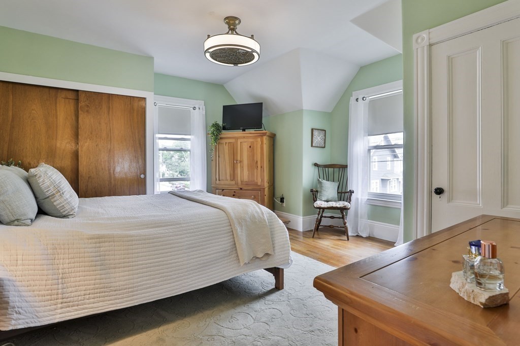 Bedroom with a large bed, green walls, wooden furniture, and a sloped ceiling.