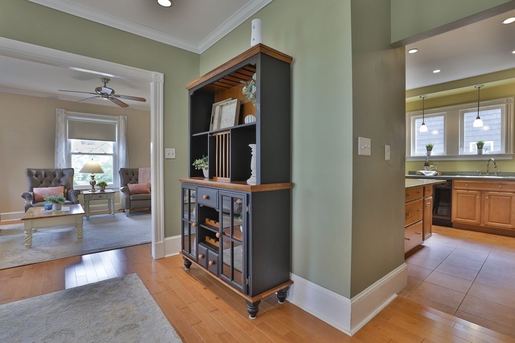 Furnished interior with a dark display cabinet between a sitting room and kitchen.