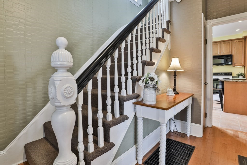 Entryway with a carpeted staircase, white balusters, and a console table beside the kitchen doorway.