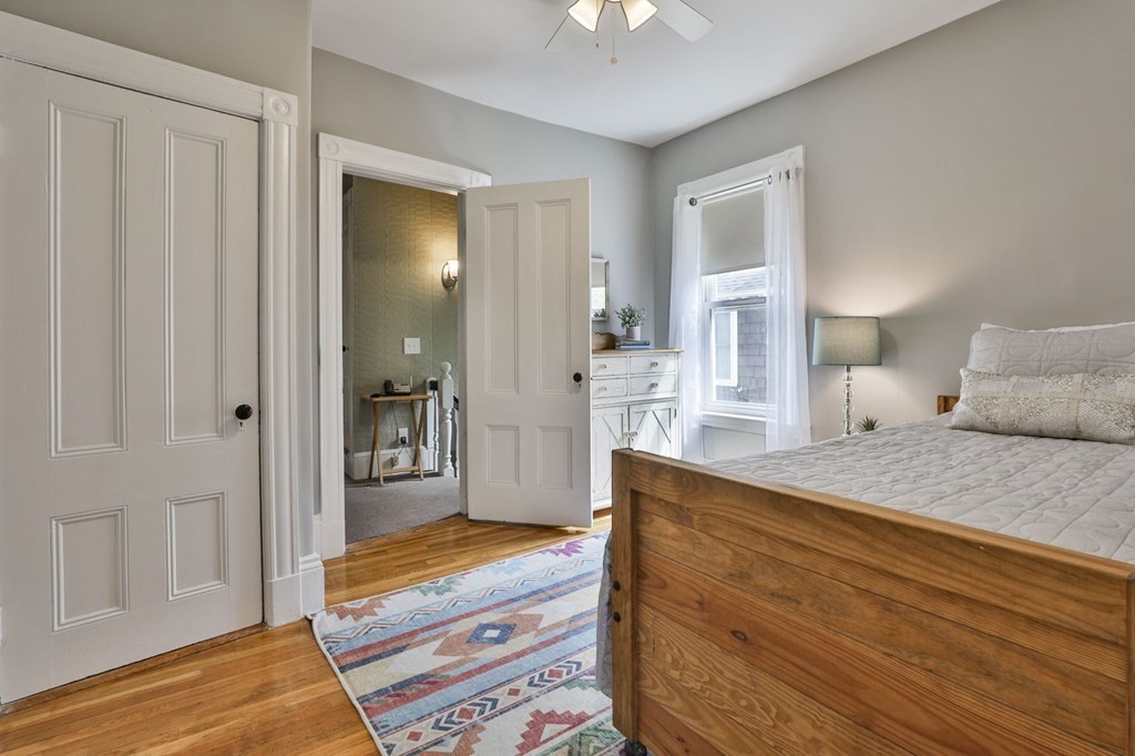 Bedroom with a wooden bed, hardwood floors, and a colorful patterned rug.