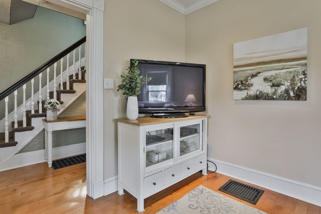 Furnished room with a television cabinet beside a staircase with white balusters and a dark handrail.