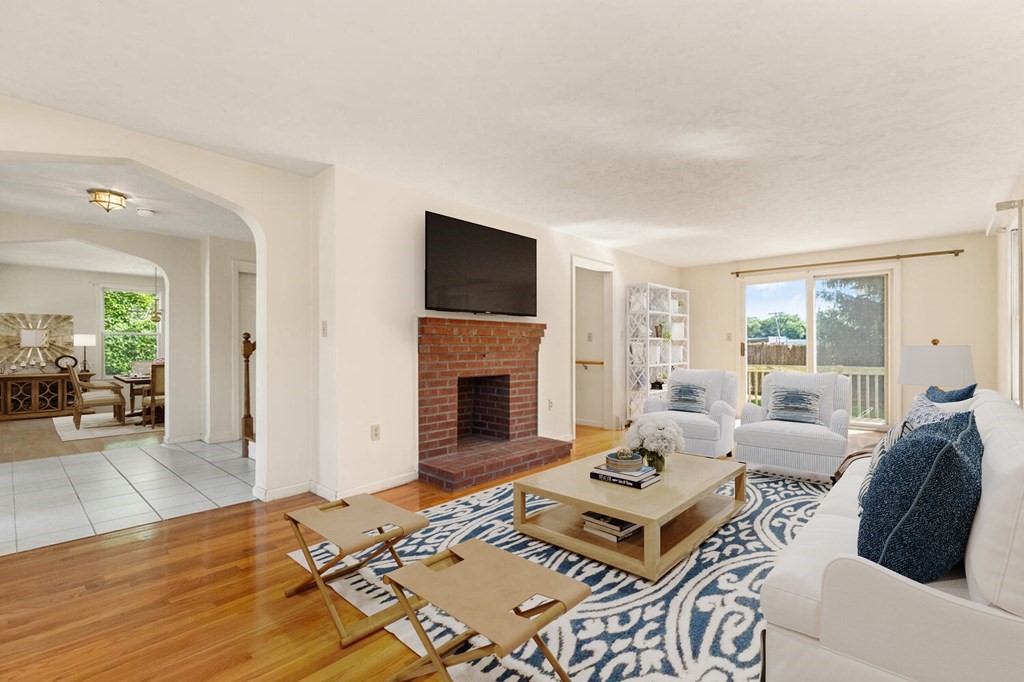 Living room with a brick fireplace, hardwood floors, and sliding doors to a deck.