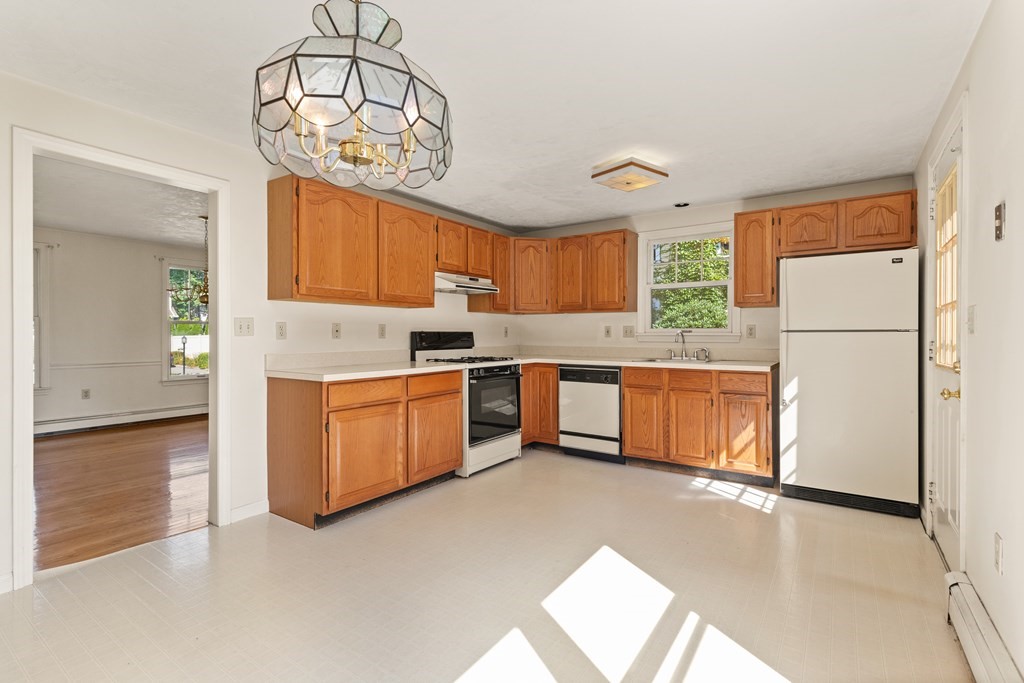 Kitchen with warm wood cabinets, white counters, and a gas range beneath a stained-glass pendant light.