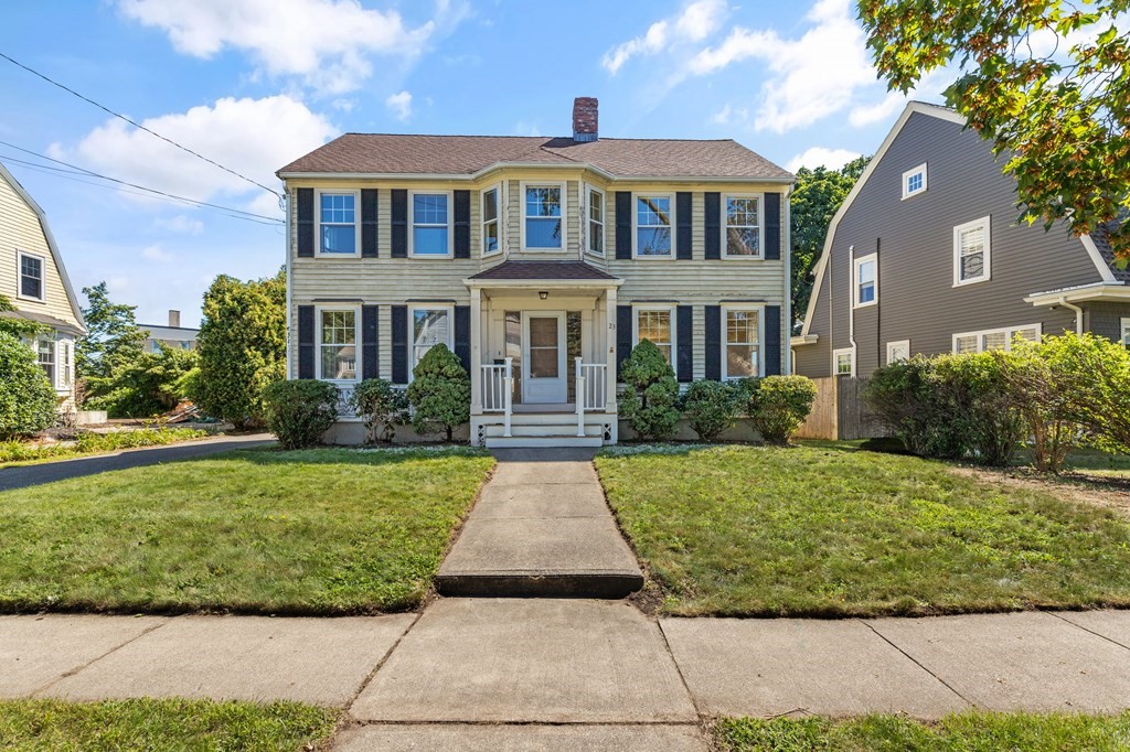Two-story house with dark shutters, a covered porch, and a walkway across the front lawn.