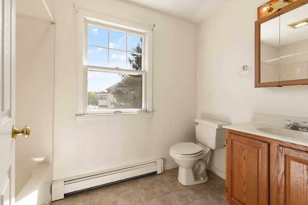 Bathroom with wood vanity, mirrored cabinet, and a large window.